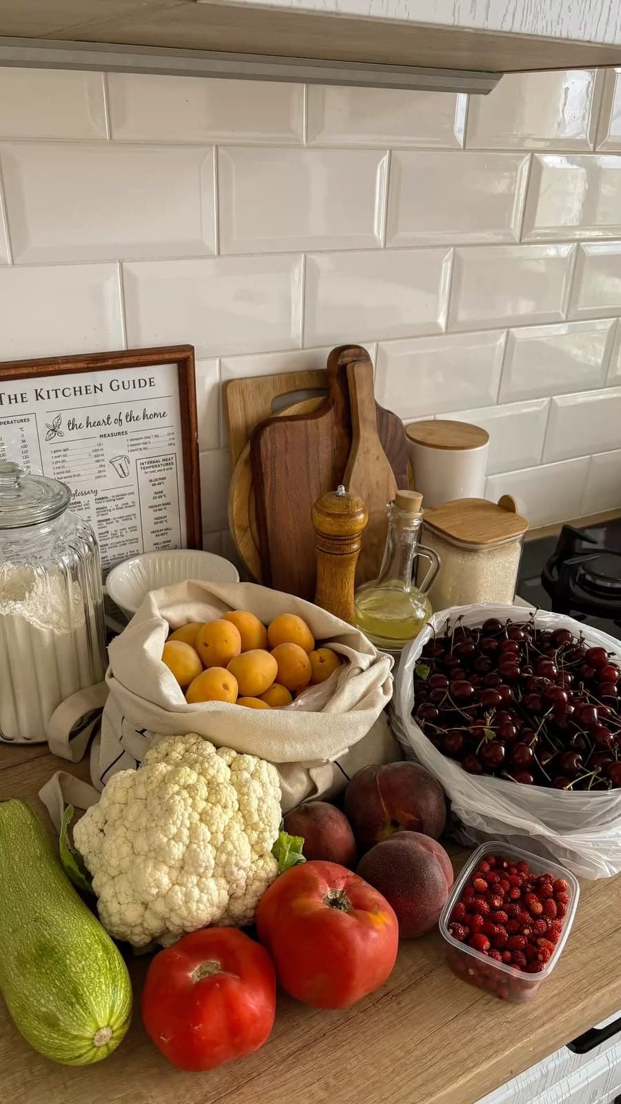 Bancada de cozinha com legumes, frutas e utensílios de madeira